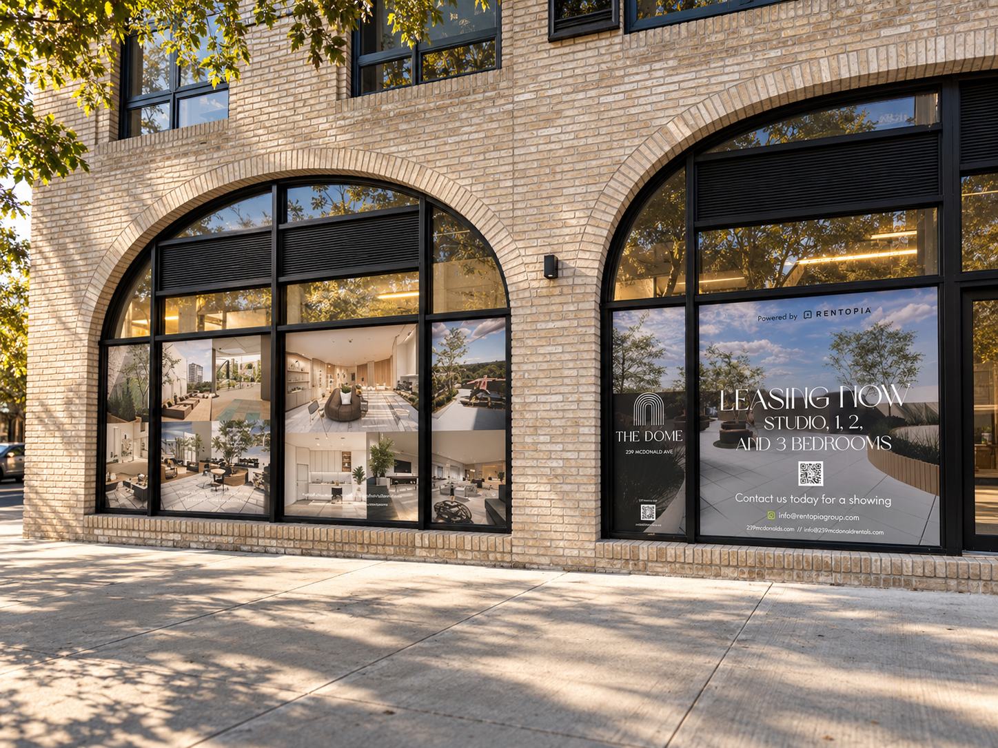 The Dome storefront window graphics across two arched windows at 239 McDonald Ave, Brooklyn: an amenity image gallery beside Leasing Now signage for studio to 3 bedroom apartments. Leasing signage by Studio Heym.