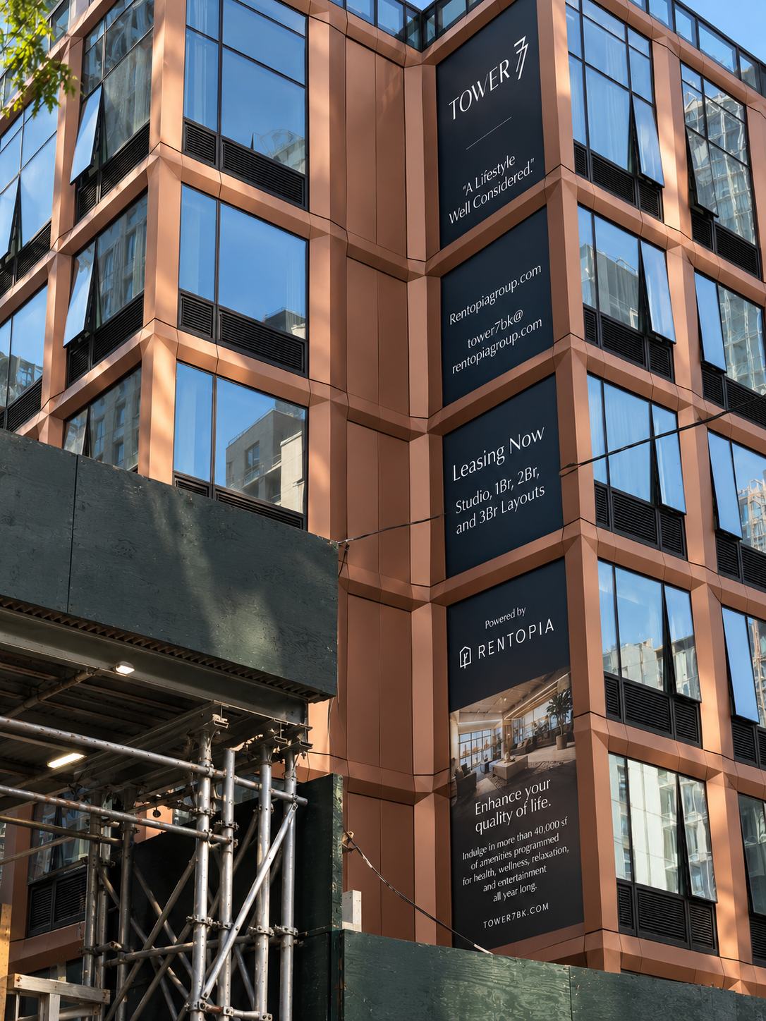 Tower 7 leasing banners stacked down a copper building corner in Brooklyn, reading Leasing Now, Studio, 1Br, 2Br and 3Br Layouts, powered by Rentopia. Building signage by Studio Heym.
